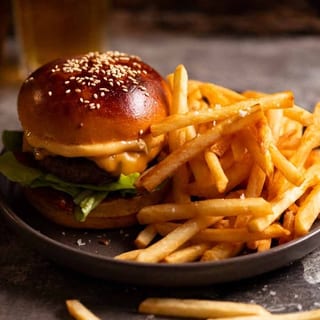 TRADITON BEEF BURGER TOPPED WITH ONION RINGS, CHEDDER CHEESE AND FRIES